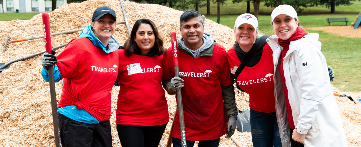 Un groupe diversifié de professionnels participe à du bénévolat à l’extérieur, reflétant une culture de collaboration et un milieu de travail où l’engagement communautaire est valorisé.