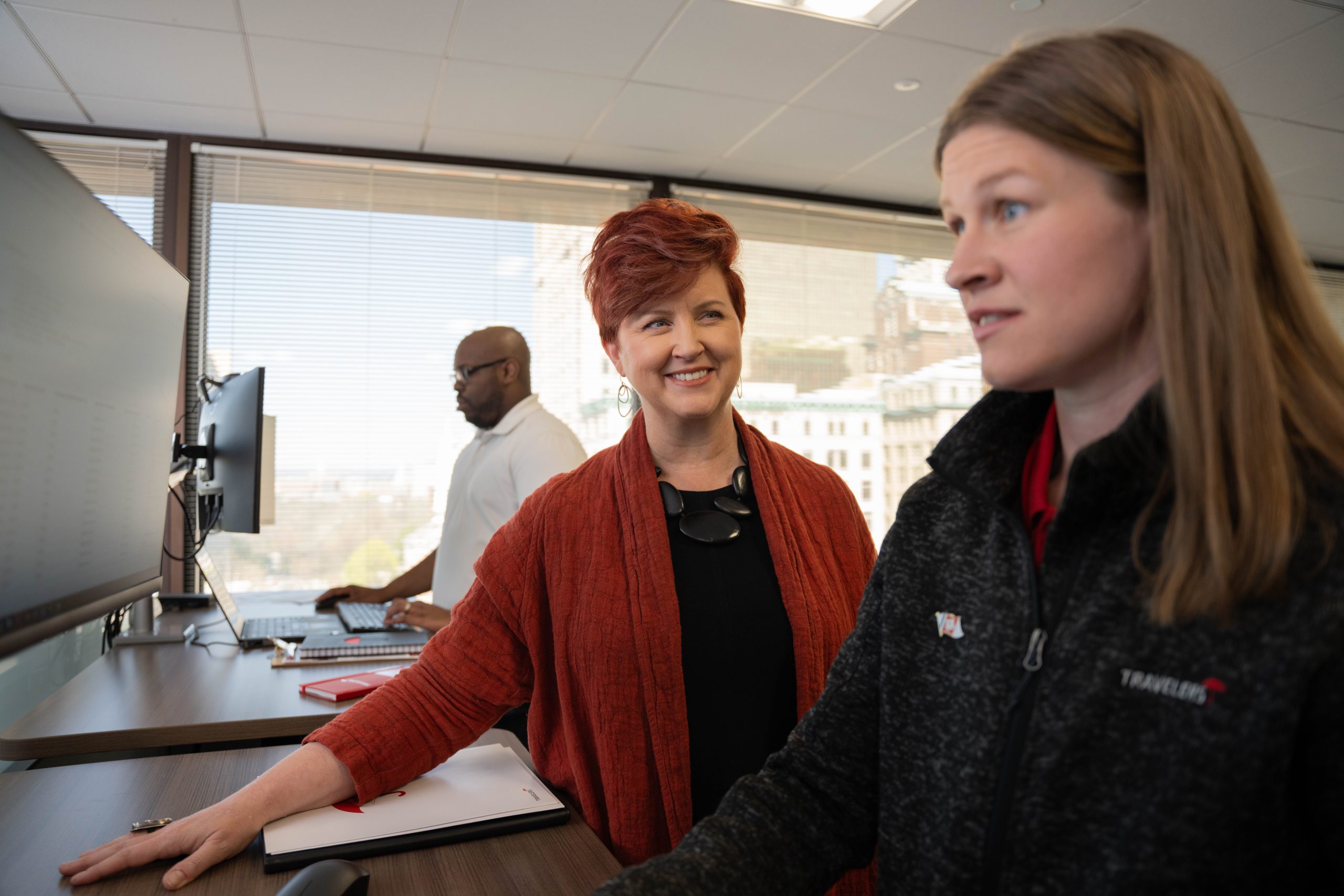 Colleagues collaborating at standing desks in a bright office.