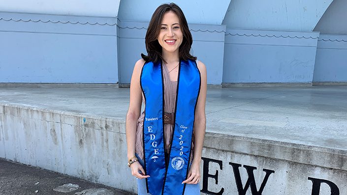 Diana Sanchez standing and smiling wearing a Travelers EDGE graduation sash.