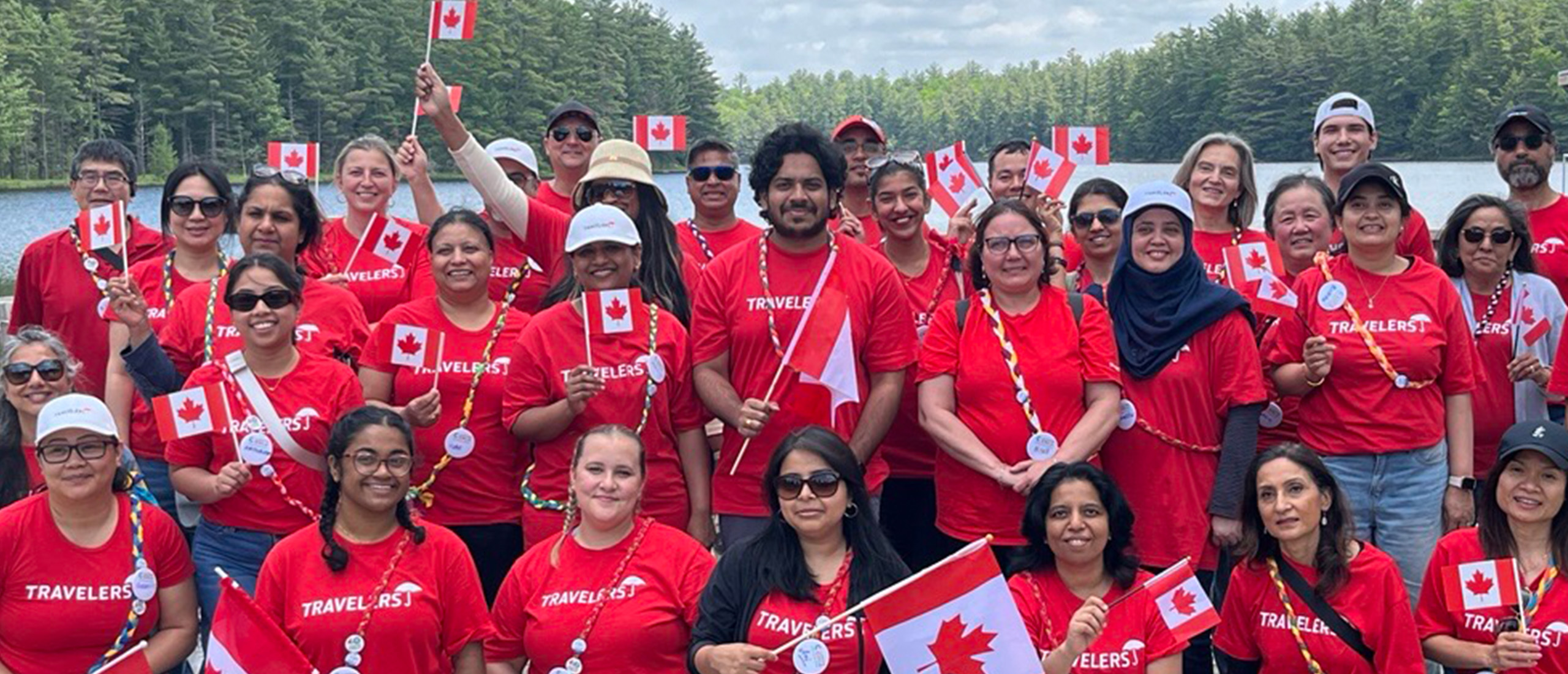 Canada_Locations_Header_Edit A group of Travelers Canada employees wave flags to show their pride in Canada and wear Travelers shirts to show their pride in Travelers.